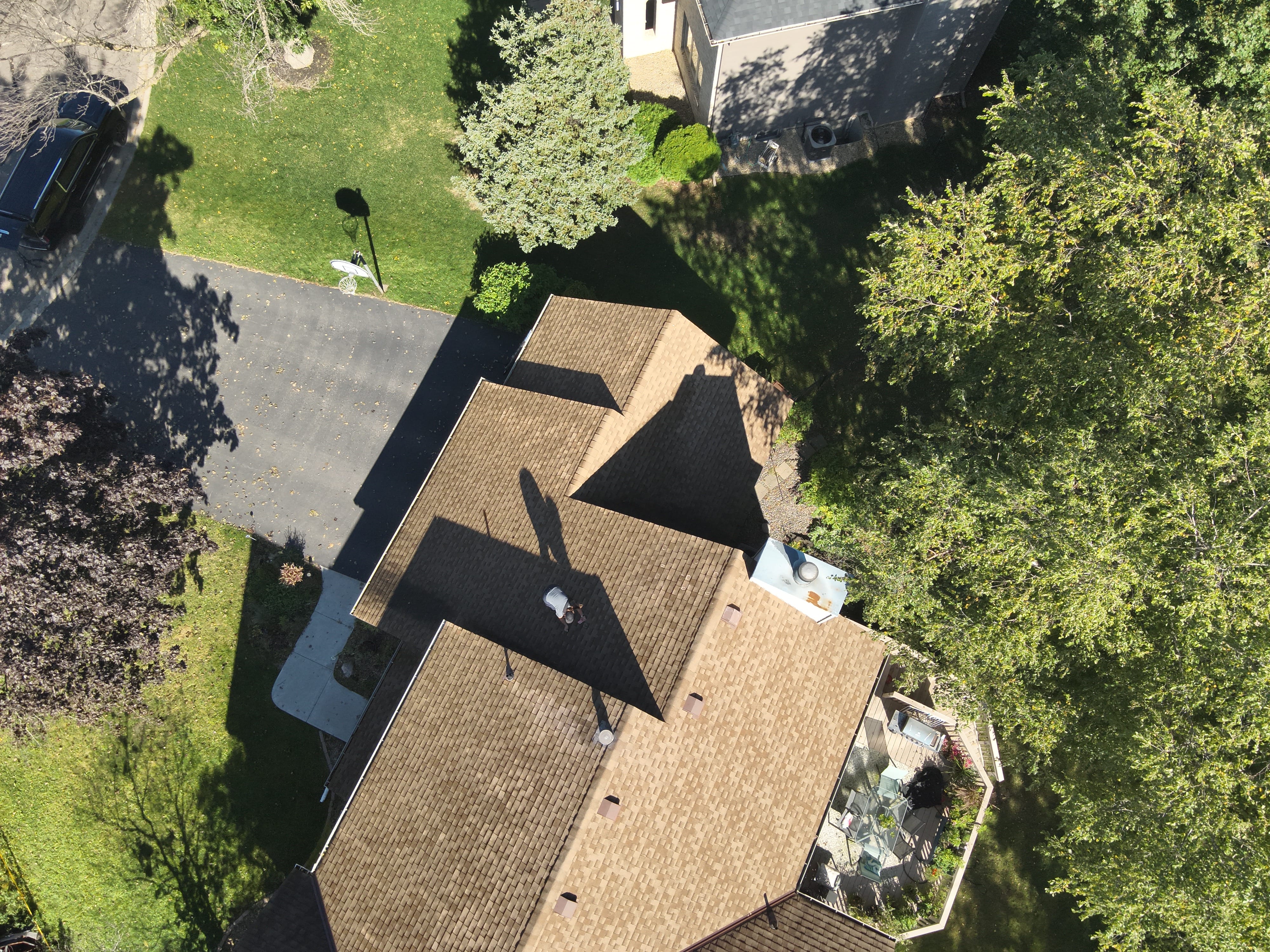 Overhead drone view of an inspector walking a residential roof for damage assessment