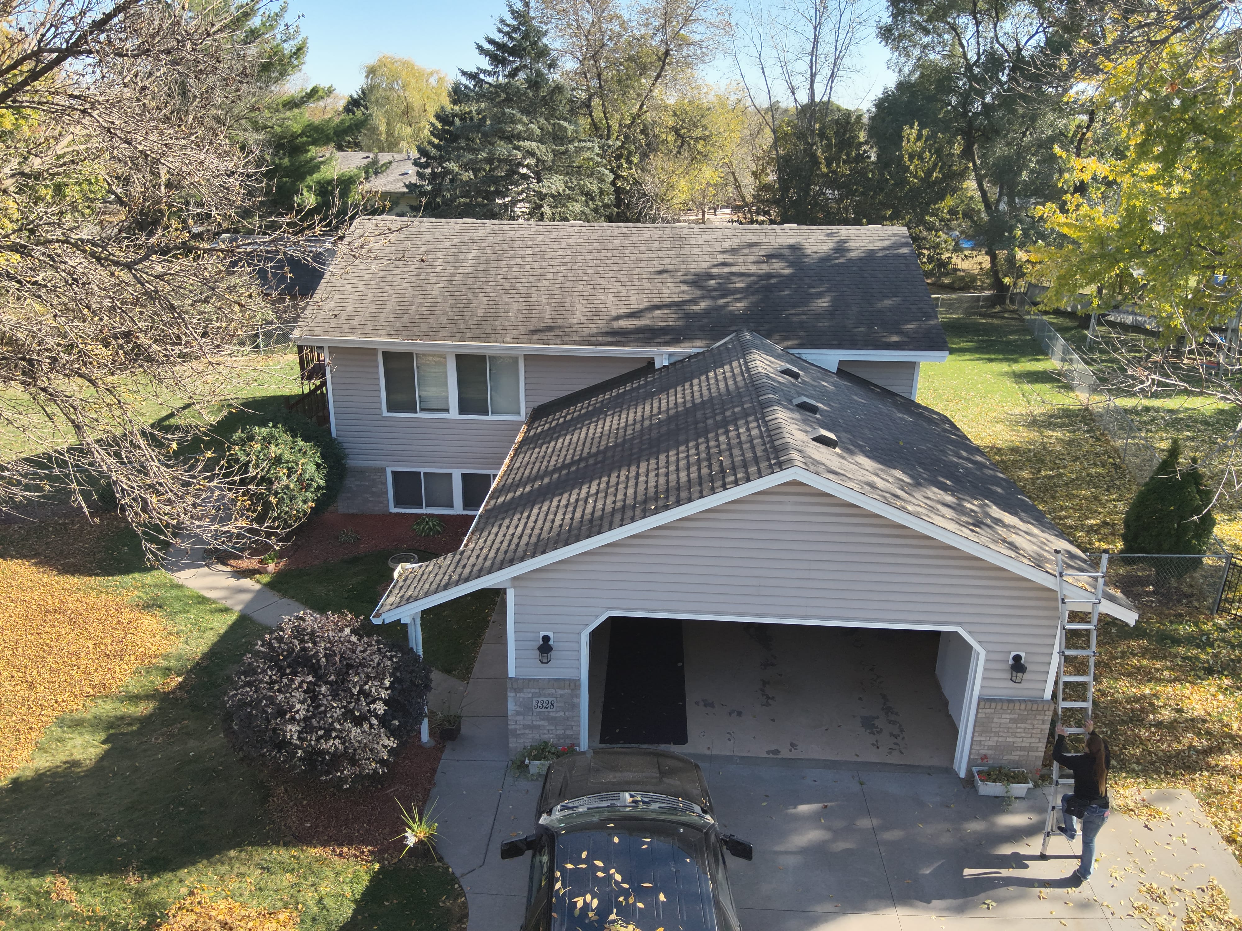 Aerial view of a Minnesota two-story home roof being inspected with a ladder set up