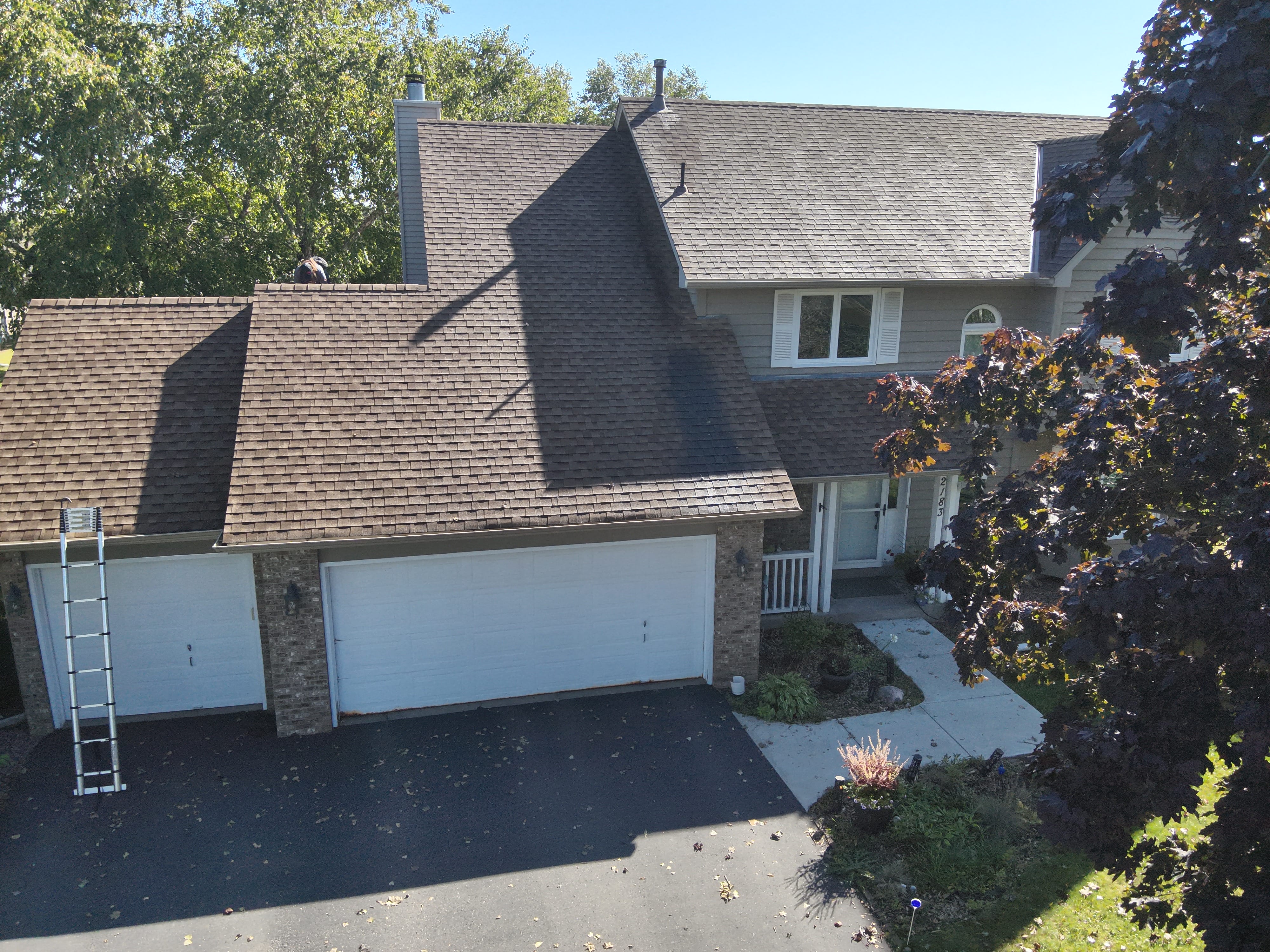 Aerial view of a large Eagan area home with shingle roof being assessed by drone