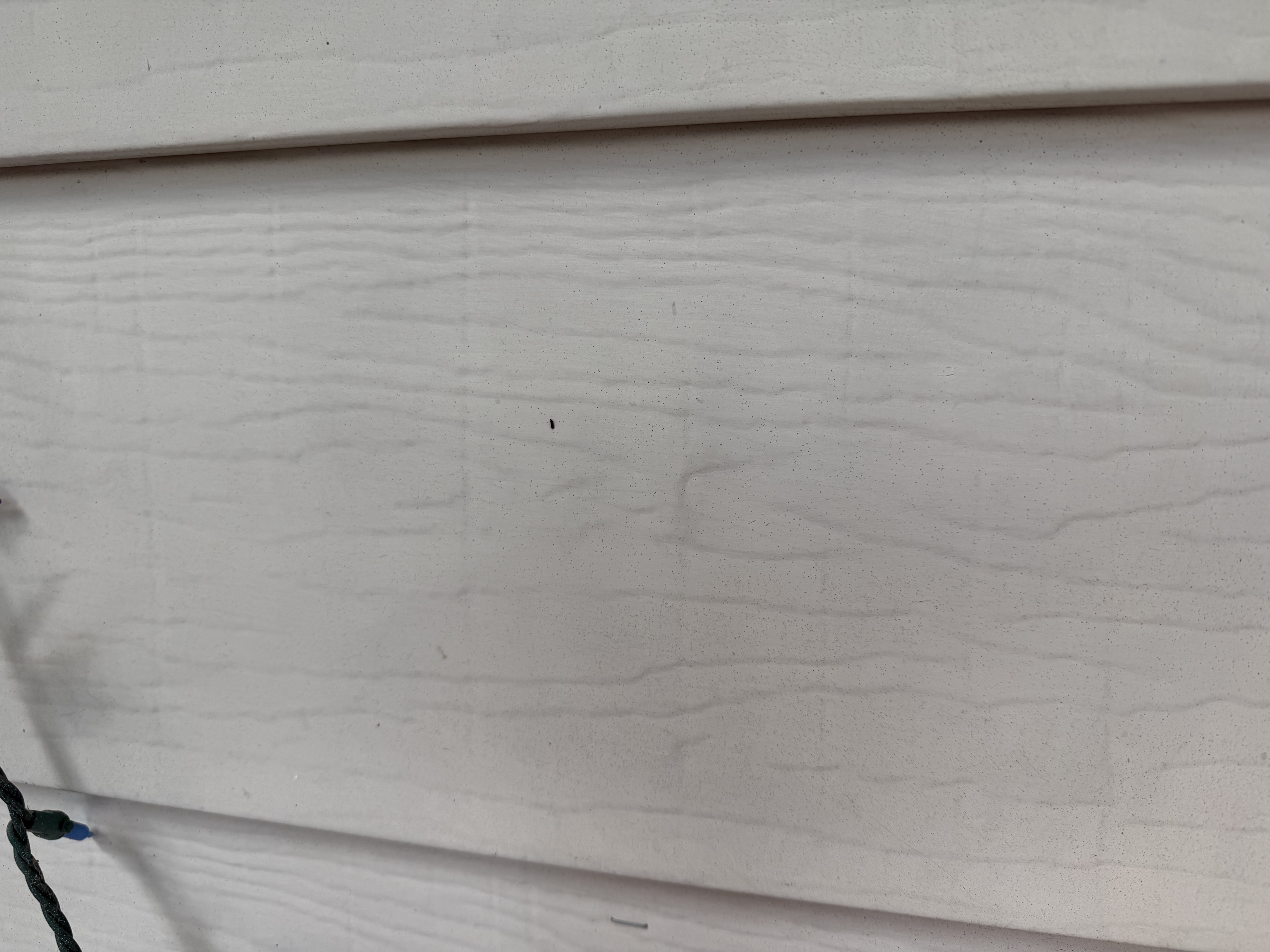 Close inspection of siding showing wind and hail damage on a Saint Paul property