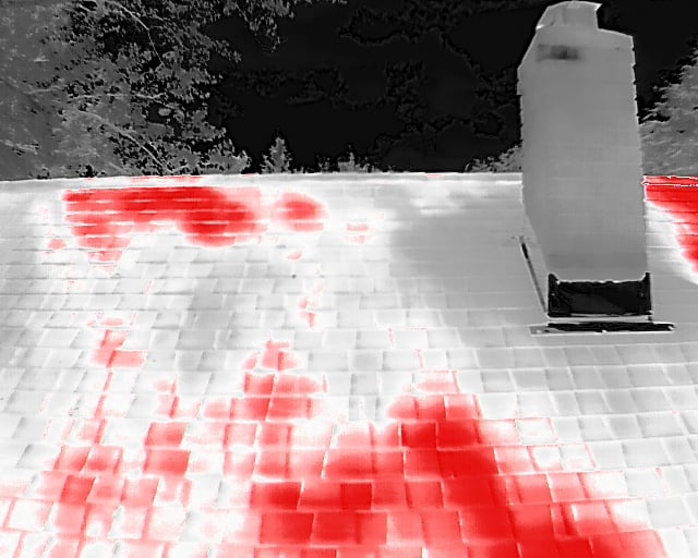 Night thermal scan of flat commercial roof showing large red moisture zones across the surface